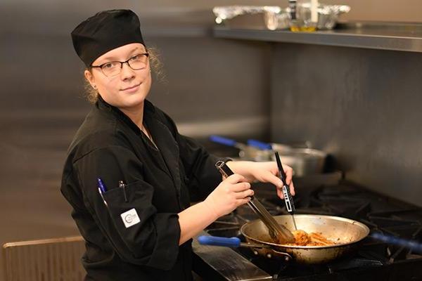 Smiling student in the culinary kitchen cooking 